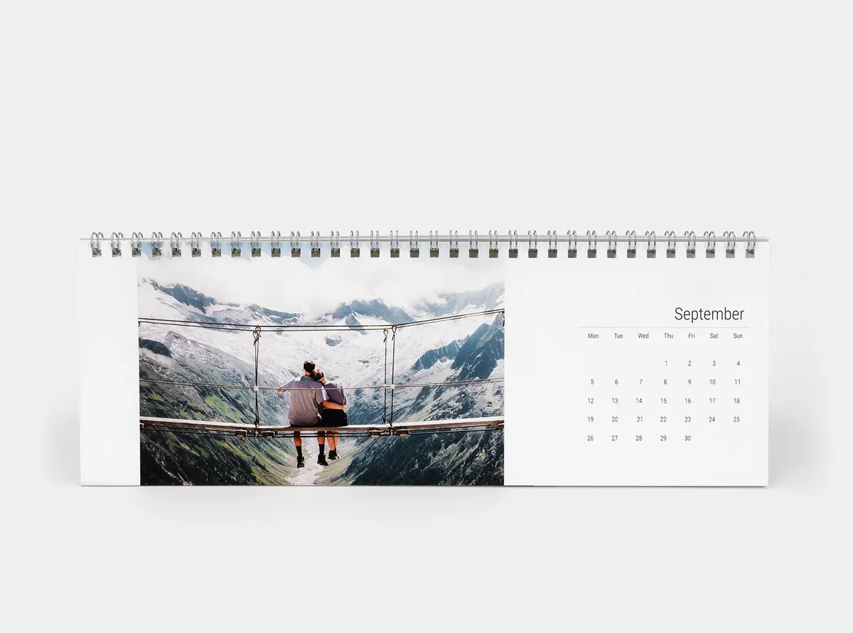 Tischkalender mit Bild eines Paares, das auf einer von Bergen umgebenen Brücke sitzt